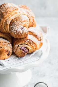 croissants piled on top of each other on a white cake platter