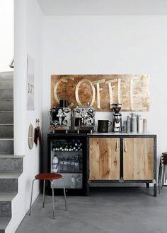 a coffee bar in the corner of a room with stairs and artwork on the wall