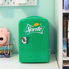 a green refrigerator sitting on top of a white shelf next to books and a camera