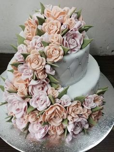 a wedding cake decorated with pink flowers on a silver platter