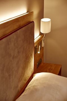 a bed that has a lamp on it next to the headboard and night stand