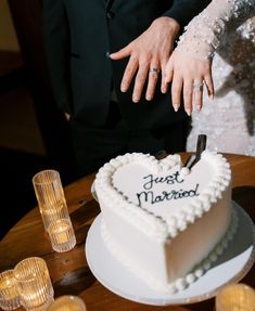 a newly married couple cutting into their heart shaped cake with the words just married written on it