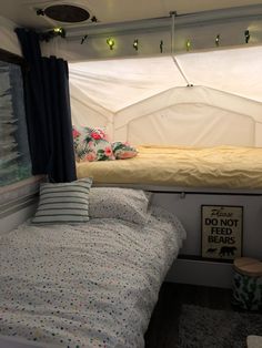 there is a small bed in the back of a camper with curtains on it