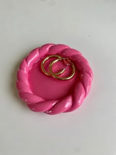 two gold rings sitting on top of a pink object