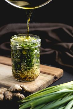 a jar filled with green vegetables being poured into it