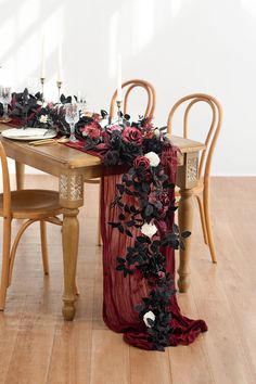 the table is decorated with black and red flowers, candles and napkins on it