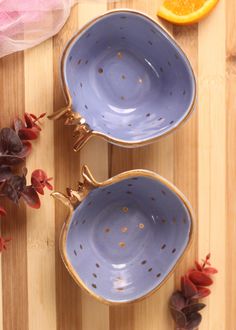 two blue bowls sitting on top of a wooden cutting board next to an orange slice