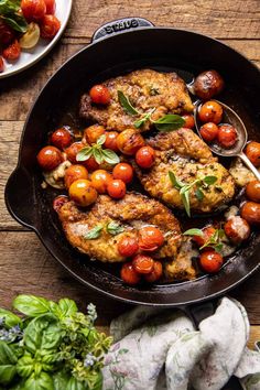 chicken and cherry tomatoes in a skillet on a wooden table with other food items