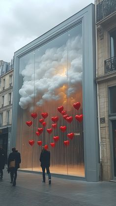 people walking past a large window with red hearts on it