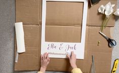 a person is making a wedding sign out of cardboard and wrapping it around the frame