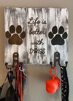 there is a dog leash holder on the wall with two dogs paw prints and an orange ball