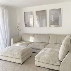 a living room with a couch and ottoman in front of two pictures on the wall