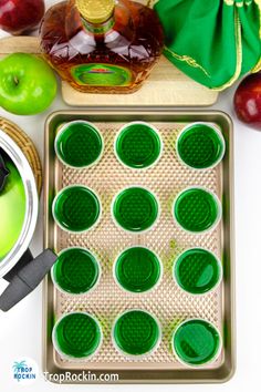 there are many green cups in the tray next to an apple and honey shaker