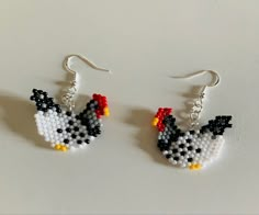 a pair of earrings made out of small beads with a chicken on the front and side