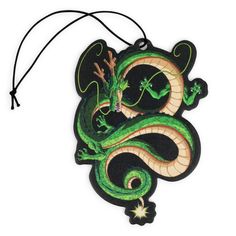 a green and black dragon ornament hanging from a string on a white background