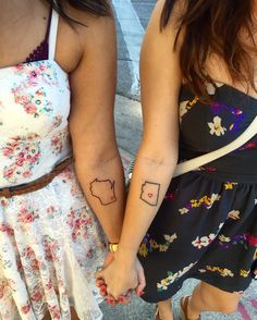 two women holding hands with tattoos on them