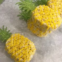 two cookies with yellow icing sitting on top of a table next to green leaves