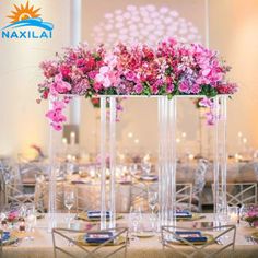 tall clear vases filled with pink and purple flowers on top of a dining table