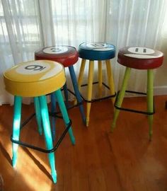 three stools with numbers painted on them sitting in front of a curtained window