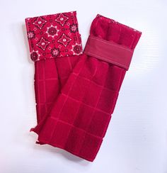 two red towels sitting next to each other on top of a white surface with one folded up