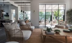 a living room with wicker furniture and large windows that look out onto the backyard