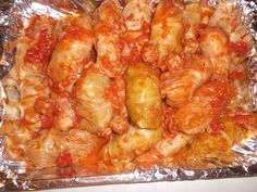 chicken wings covered in marinara sauce sitting on tin foil, ready to be cooked