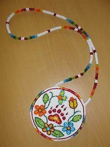 a colorful beaded necklace with flowers and leaves hanging from it on a wooden table