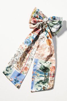 an image of a scarf tied on top of a white surface with trees and flowers