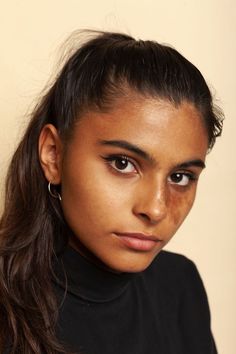 a close up of a person wearing a black shirt and hair in a pony tail