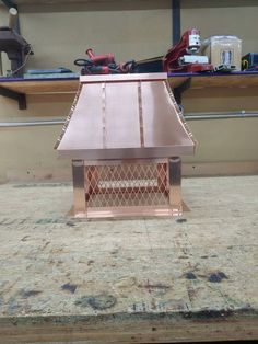 a copper colored stove top sitting on top of a wooden table next to a workbench