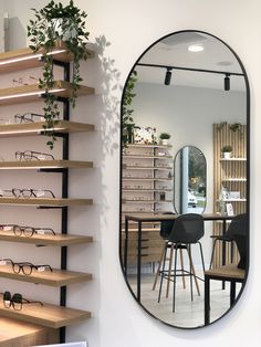 a large round mirror sitting on top of a wall next to a shelf filled with glasses