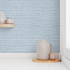 two white vases are sitting on a shelf in front of a blue striped wall