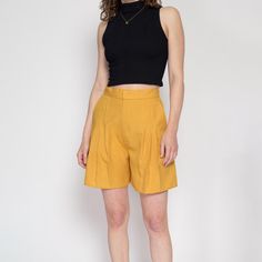 Vintage 80s high waisted mustard yellow shorts with statement pleating at the front.  Measurements and Condition: Fits like: Women's medium Fabric: Feels like poly/rayon Brand: None Condition: Very good, the pleats have begun to fall out at the bottom of the legs but can be easily pressed back into place. Waist: 28" Hips: 39" - taken at the bottom of the zipper opening Rise: 14" Inseam: 5" Shown on a 5'8" model with measurements of 34"-26"-37", usually wears a size small. See our FAQ for more in Black Babydoll, Yellow Shorts, Pleated Shorts, Long Shorts, Skorts, Babydoll Dress, Mustard Yellow, Short Outfits, Mustard