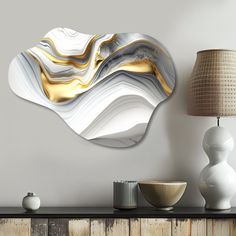 a white and gold art piece sitting on top of a wooden table next to a lamp