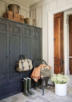 a black cabinet sitting next to a white vase filled with flowers and two purses