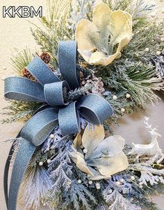 a christmas wreath with blue ribbon and white flowers