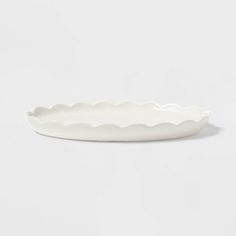 a white oval dish with scalloped edges on a plain surface, ready to be used as an appetizer