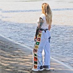 a woman standing on the beach with her back to the camera and looking at the water