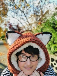 a woman wearing a knitted fox hat with black rimmed glasses and a striped shirt