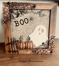 a wooden frame with a ghost and pumpkins in it on top of a table