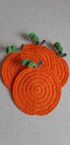 three crocheted pumpkin coasters sitting on top of a table