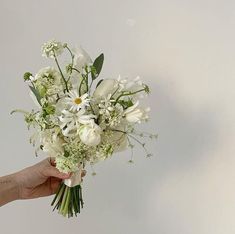 a hand holding a bouquet of white flowers