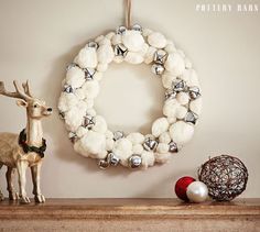 a christmas wreath and ornaments on a mantel with a deer figurine next to it