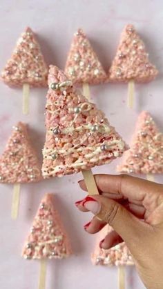 a hand holding a toothpick with pink and white sprinkles on it