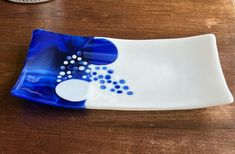 a blue and white plate sitting on top of a wooden table next to a coin