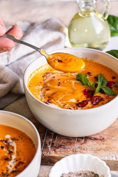 a person spooning some soup out of a bowl