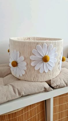 a basket with white flowers on it sitting on top of a wooden table next to pillows