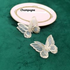 two butterflies sitting on top of a green table cloth next to a white and gold plate