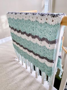 a crocheted blanket hanging from the side of a banister in a house