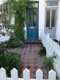 a white house with a blue door surrounded by greenery